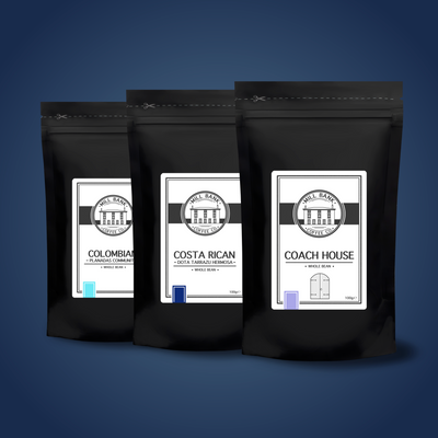 Three black coffee sample bags labeled as 'COLOMBIAN', 'COSTA RICAN', and 'COACH HOUSE'.