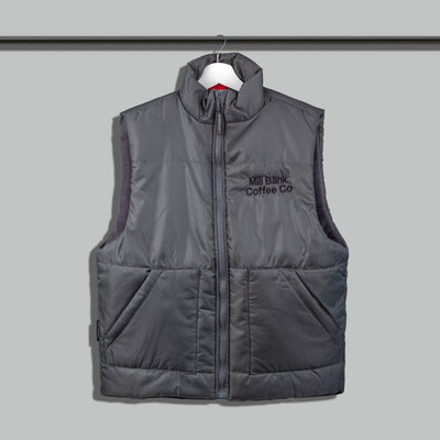 A gray fleece lined gilet with a front zipper and a logo patch on the chest area, displayed on a hanger.